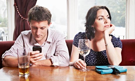 couple ignoring each other while one uses a smartphone