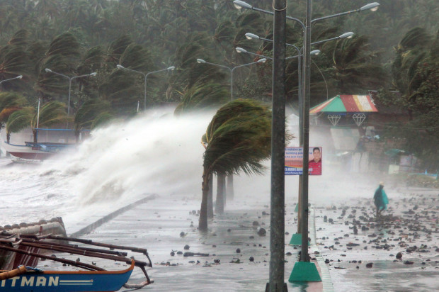 A resident walks past high waves pounding the sea wall amidst strong winds as Typhoon Haiyan hit the city of Legaspi, Albay province, south of Manila on November 8, 2013.  photo:  huffington post