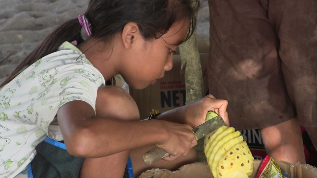 10 year old girl serving up pineapples at Mawi, Lombok