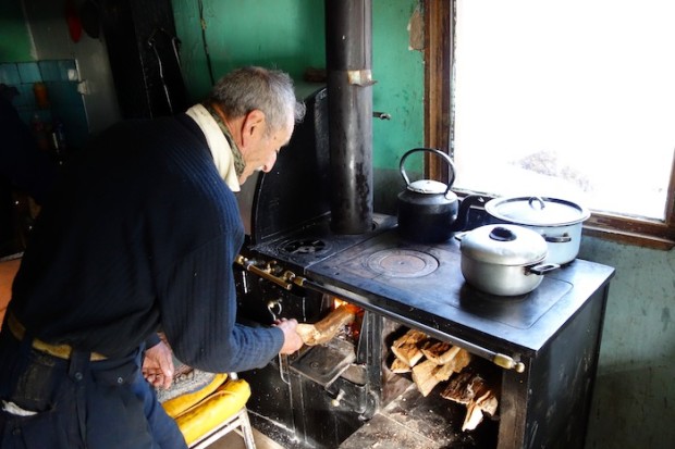El Abuelo loading the wood cooking stove at his home in the valley.