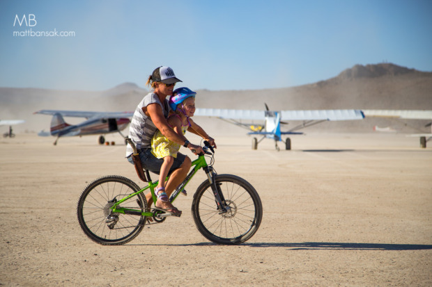 Lel Tone giving Jessica and Kevin Quinn's daughter a bike tour of the playa.