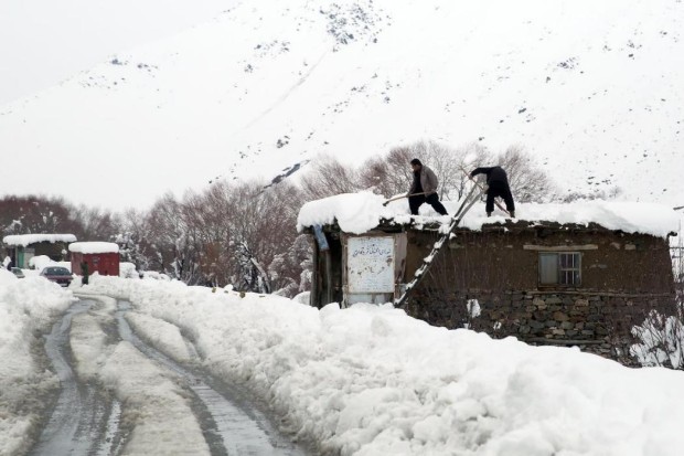 Afghan men clean off the snow from their roof tops in a village close to an avalanche site in Panjshir province north of Kabul, Afghanistan, Wednesday, Feb. 25, 2015. Avalanches caused by a heavy winter snow killed at least 124 people in northeastern Afghanistan, an emergency official said Wednesday, as rescuers clawed through debris with their hands to save those buried beneath. (AP Photo/Massoud Hossaini)