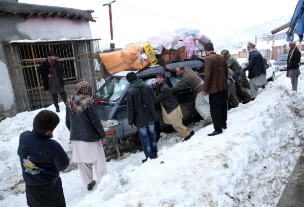 Afghan men push a car which became stuck near an avalanche site in Panjshir province north of Kabul, Afghanistan, Wednesday, Feb. 25, 2015. Avalanches caused by a heavy winter snow killed at least 124 people in northeastern Afghanistan, an emergency official said Wednesday, as rescuers clawed through debris with their hands to save those buried beneath. (AP Photo/Massoud Hossaini)