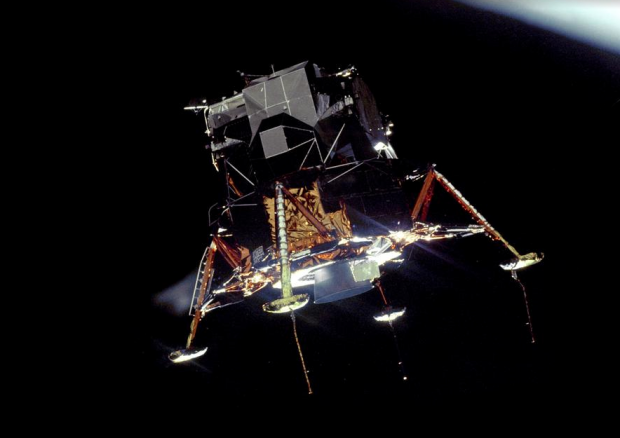 The Apollo 11 Lunar Module (LM) "Eagle", in a landing configuration is photographed in lunar orbit from the Command and Service Modules (CSM) "Columbia". Inside the LM were Commander, Neil A. Armstrong, and Lunar Module Pilot Edwin E. "Buzz" Aldrin Jr. The long "rod-like" protrusions under the landing pods are lunar surface sensing probes. Upon contact with the lunar surface, the probes send a signal to the crew to shut down the descent engine. 