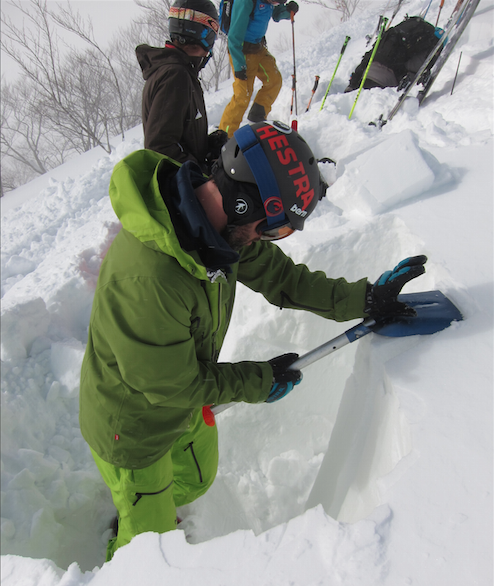 Guide Miles Clark digging a snow pit in Japan on an unstable day.