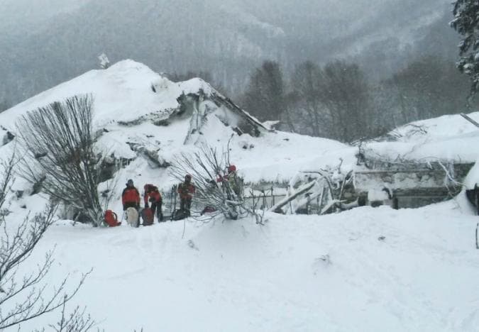 Members of Lazio's Alpine and Speleological Rescue Team stand in front of the Hotel Rigopiano in Farindola, central Italy, hit by an avalanche, in this January 19, 2017 handout picture provided by Lazio's Alpine and Speleological Rescue Team. Soccorso Alpino Speleologico Lazio/Handout via REUTERS