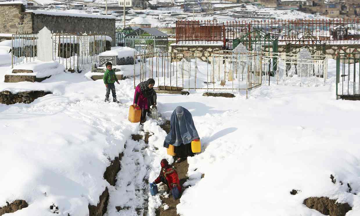 A woman and her children carry containers of water on the outskirts of Kabul, Afghanistan, on Monday. Avalanches have killed more than 100 people in Afghanistan and Pakistan.