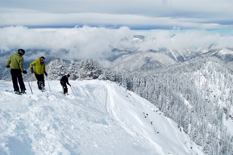 Skiers overlooking drop, Taos, app, 