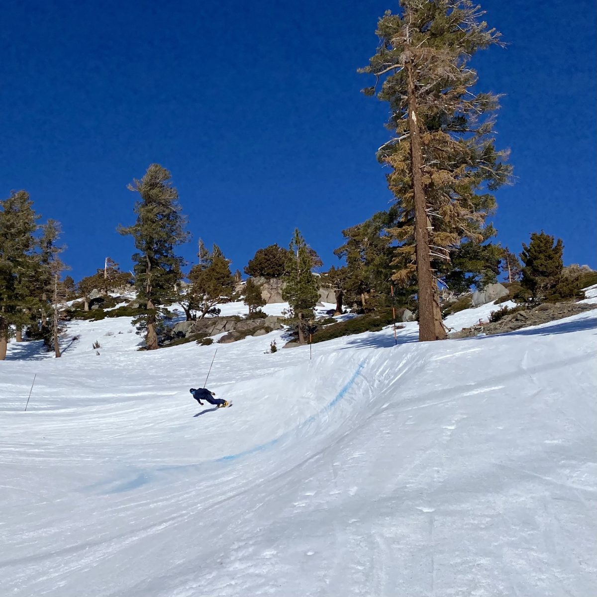 Snowboarder rounding a turn on Palisades Tahoe's boardercross course