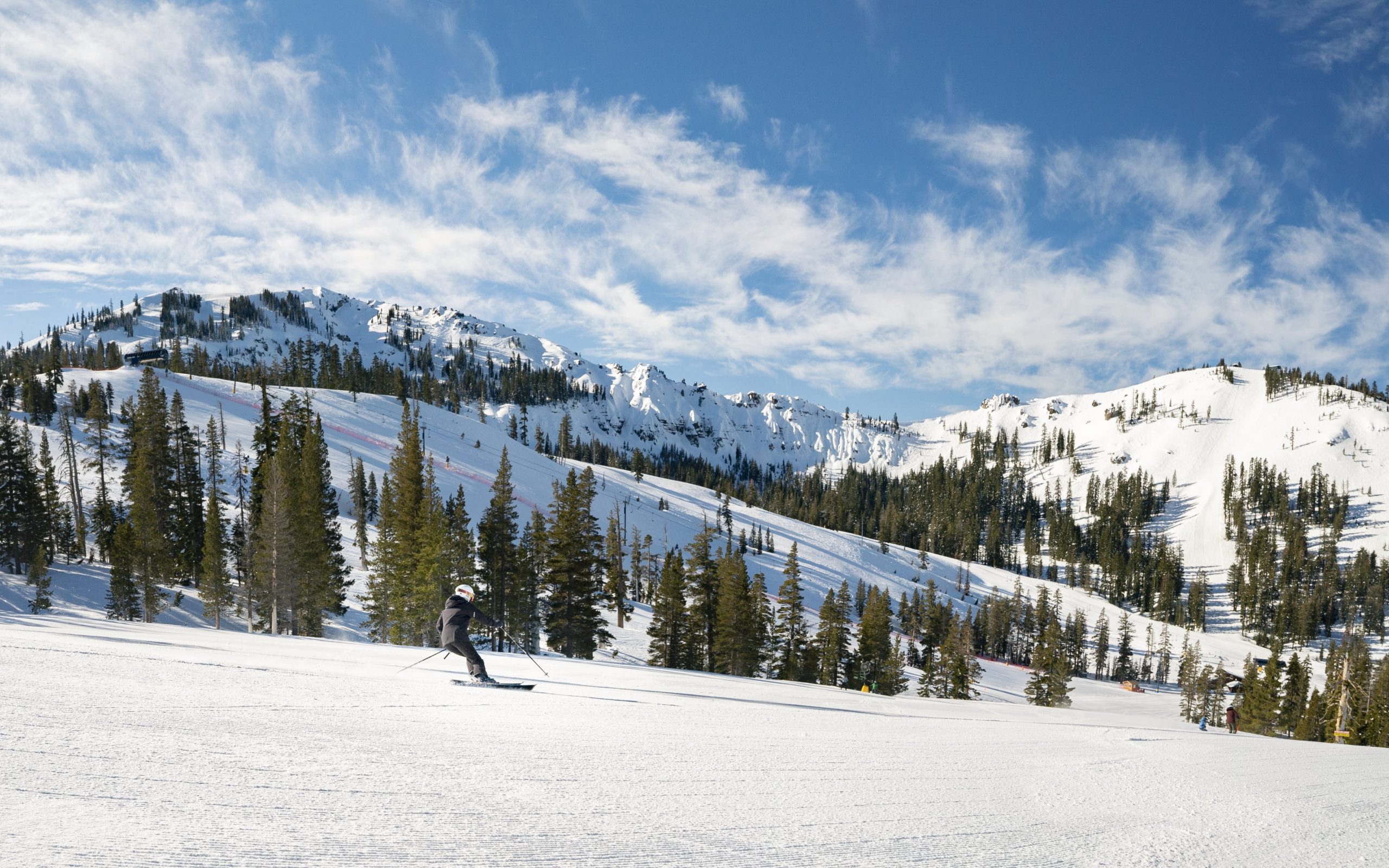 Skiing groomers with palisades looming in background