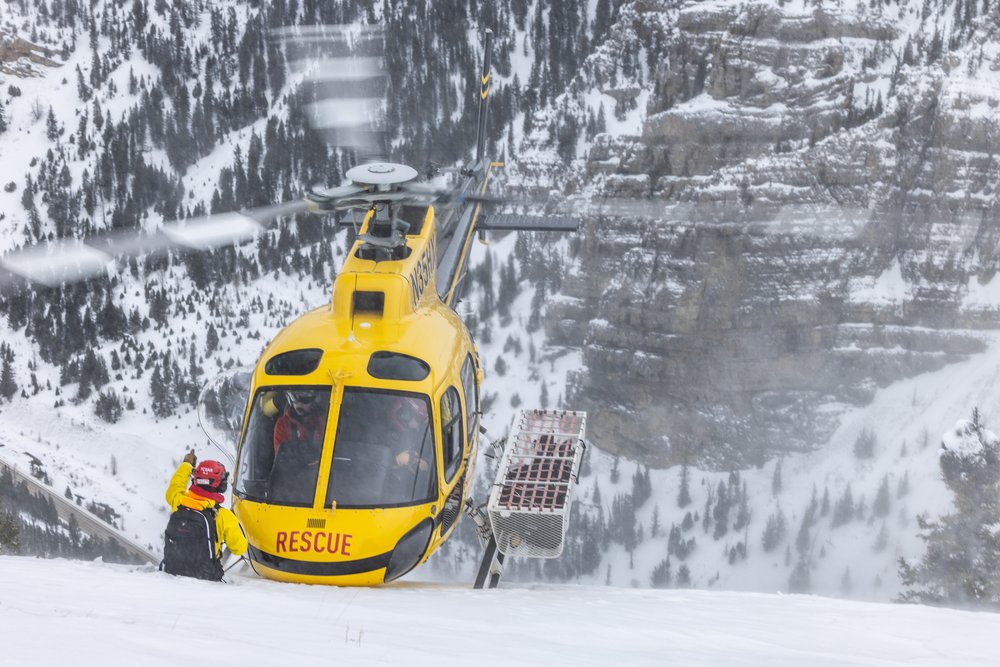 TCSAR rescuer next to helicopter in the Teton backcountry