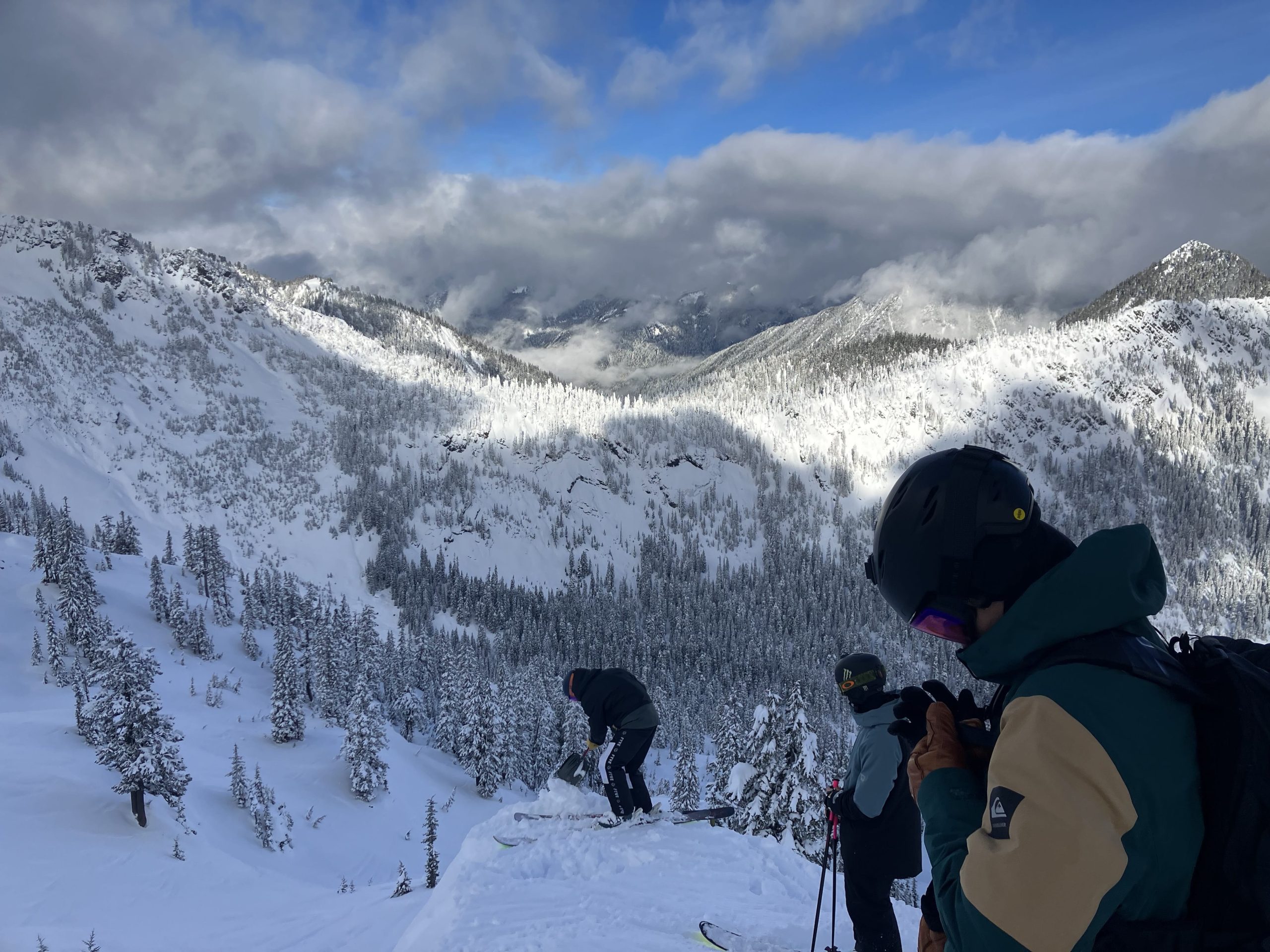 Snow-filled valley with a couple of friends at the top of a drop.