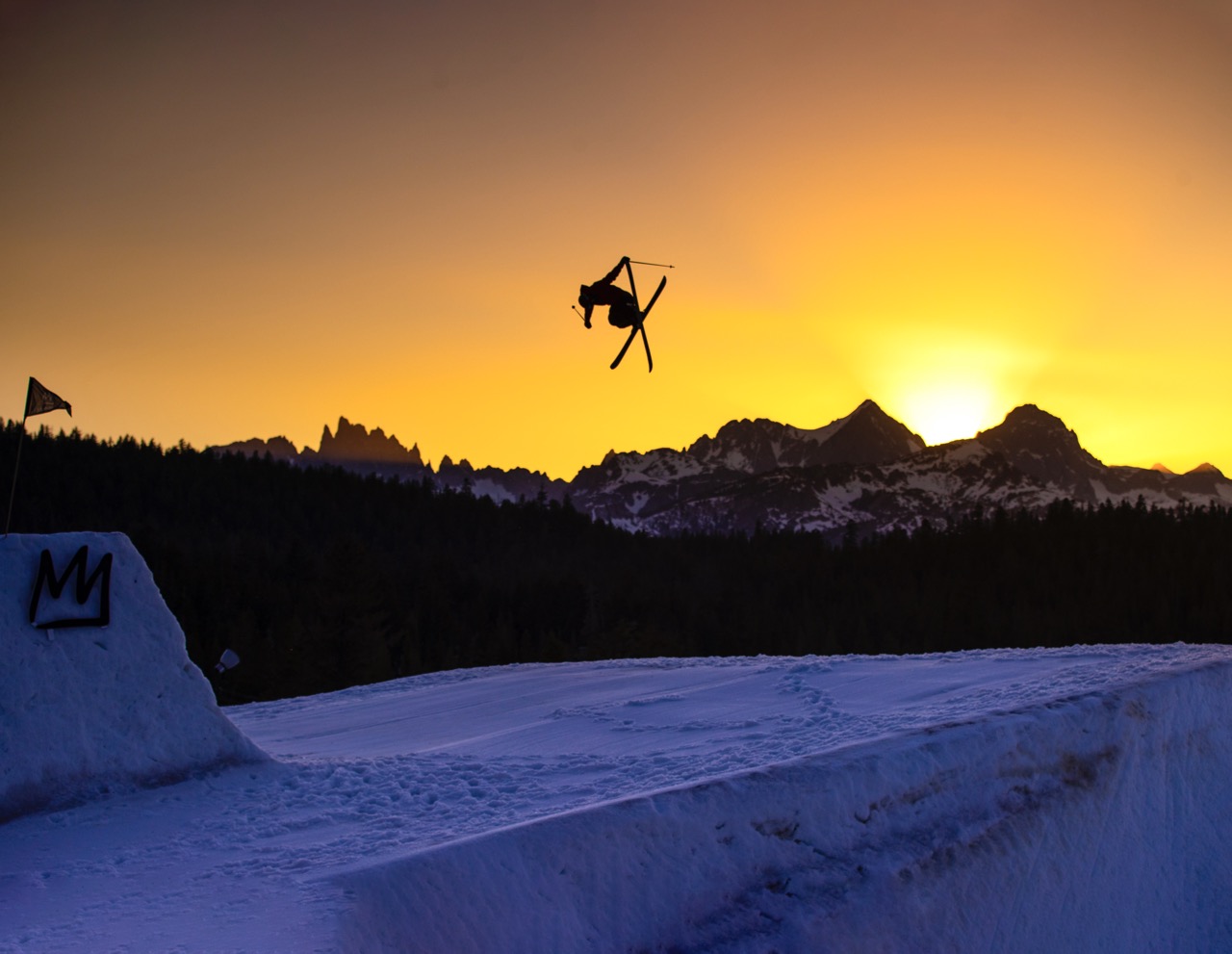 skier jumping in front of mountain sunset