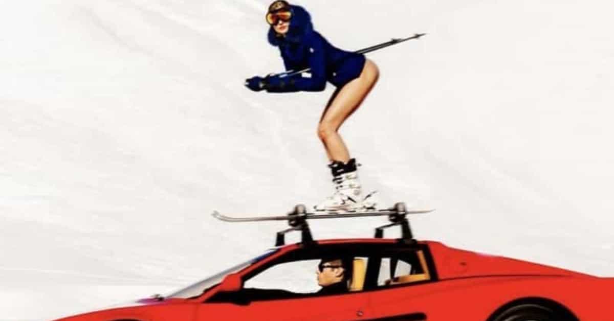 Half naked woman skiing on top of a red Ferrari