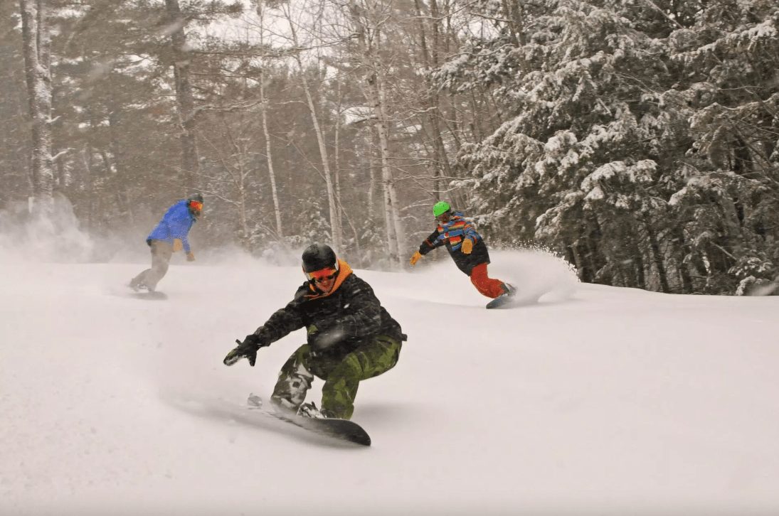 Snowboarders make powder turns at King Pine, NH.