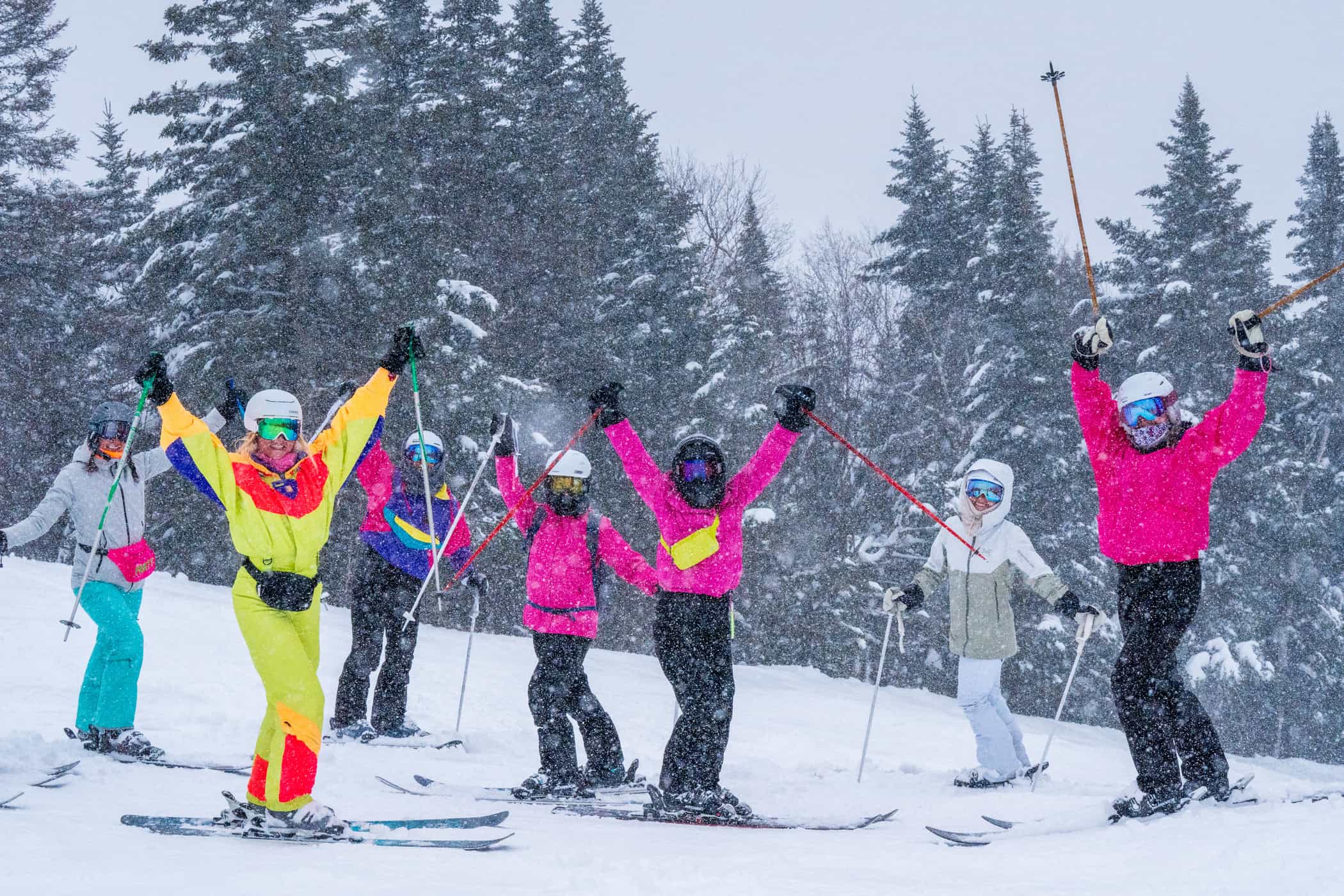 skiers in bright clothing celebrating snow