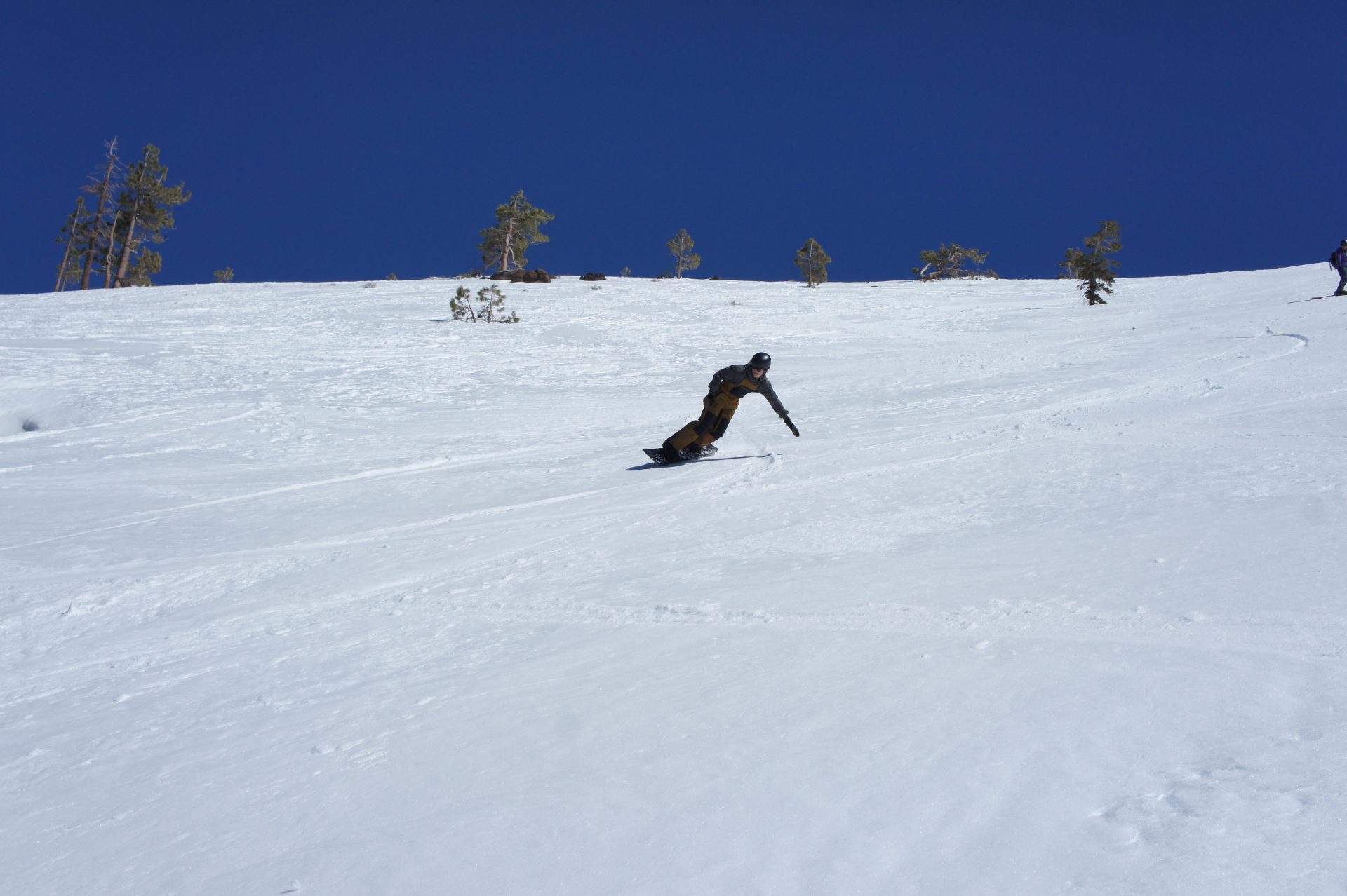 snowboarder laying out in a turn on a bluebird spring day