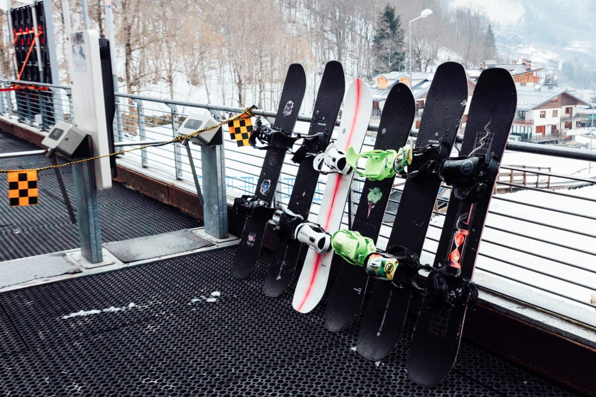 A line up of Ride Snowboards against a railing in a snowy backdrop.