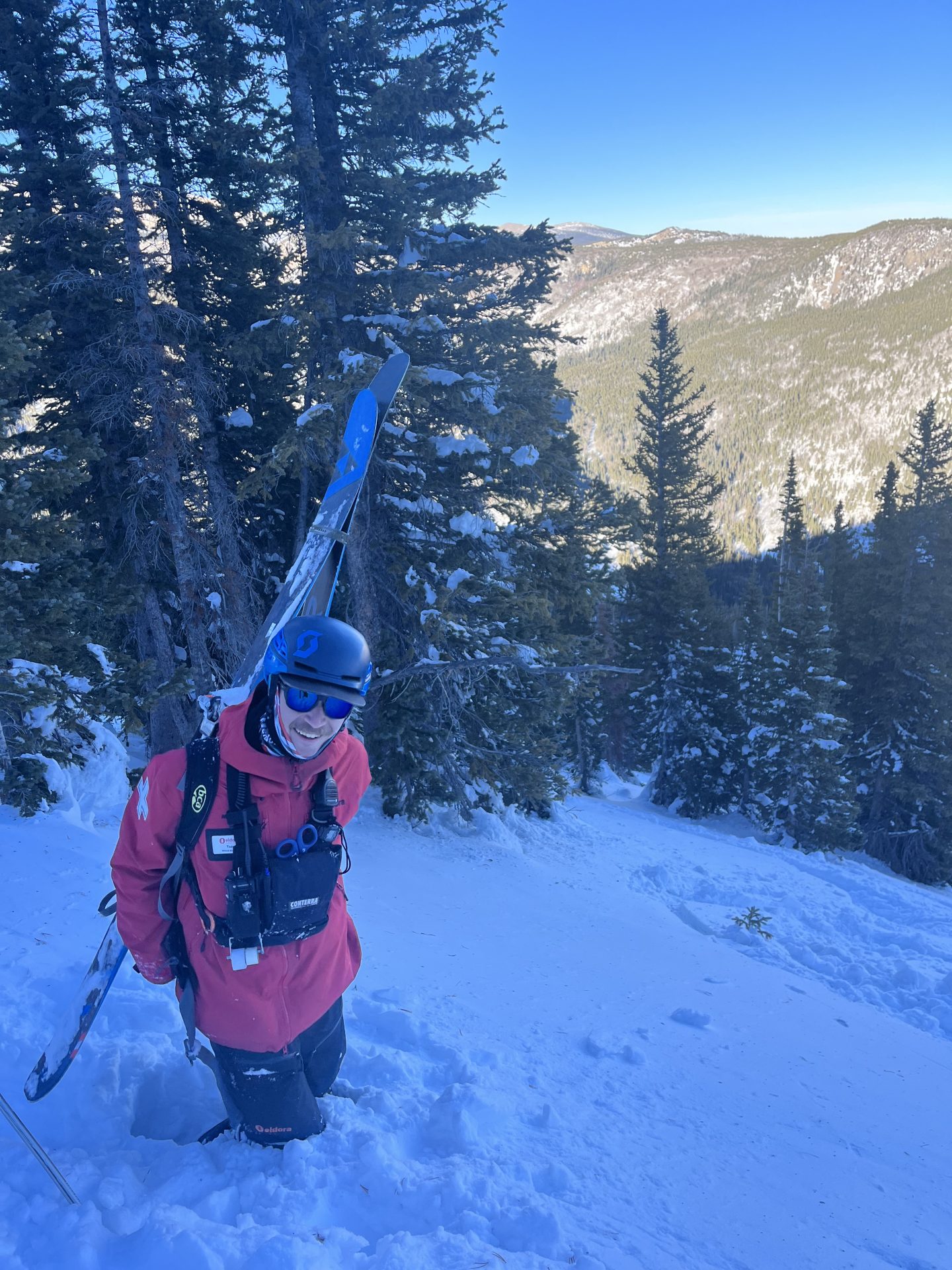 eldora ski patroller hiking with skis in deep snow