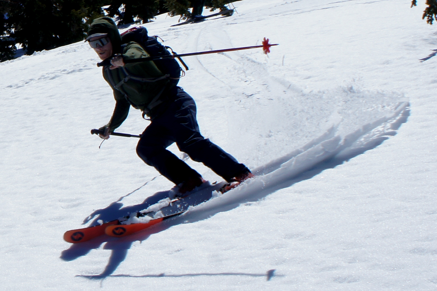 skier throwing up wave of slush in bright sunshine