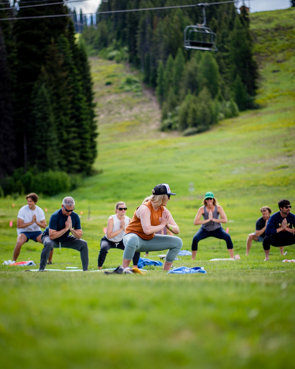 people doing yoga on the grass on a mountainside