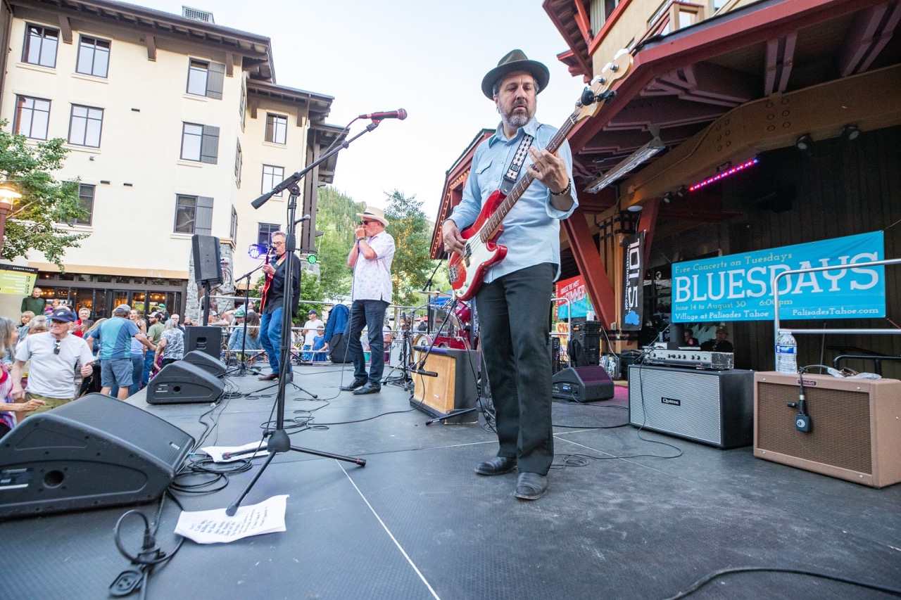 a band on stage at palisades tahoe with a guitarist in the foreground playing blues