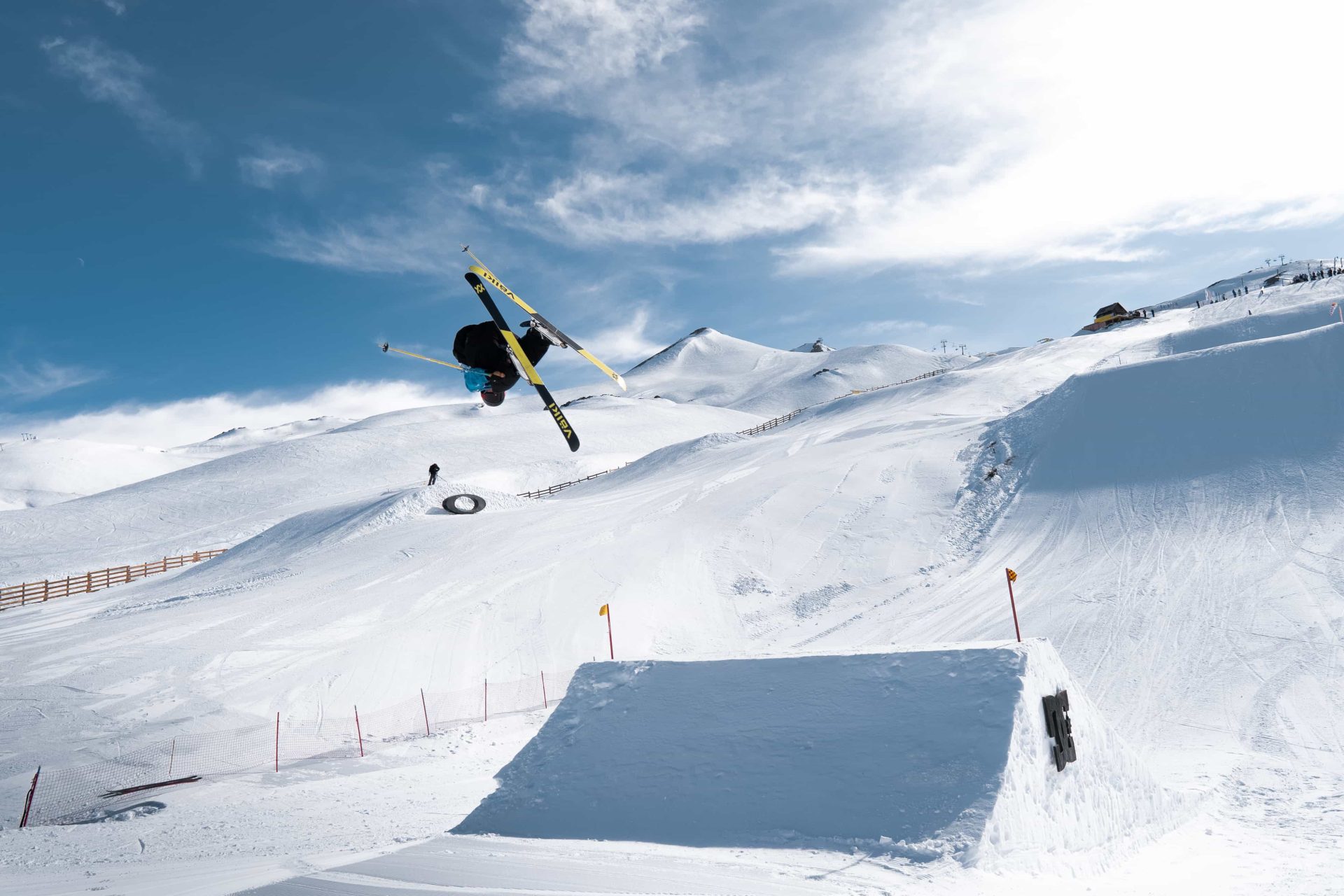 Skier gets big air of a jump with cloudy blue skies in the background at Valle Nevado Andes Cup