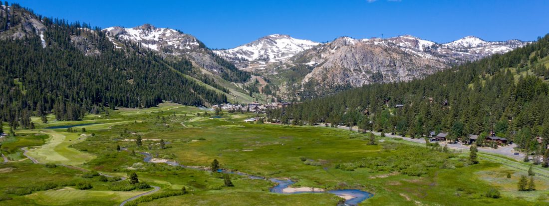 landscape view of olympic valley with some snow in the mountains and green meadows