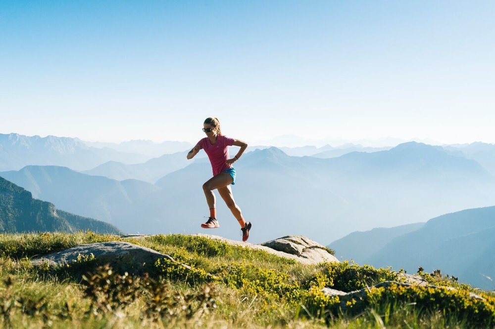 woman running on a green mountain rideline