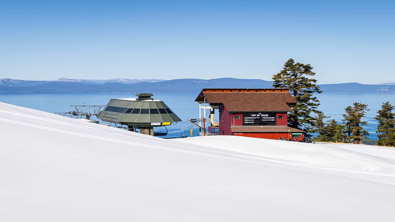 snow slope and lift shack at heavenly resort with lake tahoe in the background