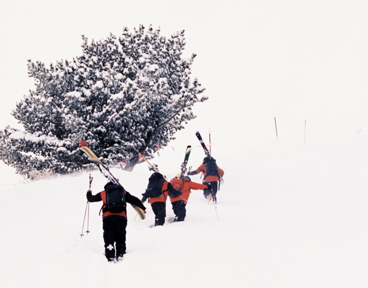 ski patrollers hiking up hill in deep snow